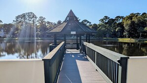 A wooden bridge leading to a gazebo over a calm lake, surrounded by trees. - Shipyard: 271 Evian Island Villa-Relaxing Setting Weekly Rates Discounted (Hilton Head Island)
