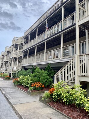 A multi-story building with balconies and a flagpole.