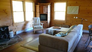 A cozy cabin interior with a sofa, a chair, a television, and a fireplace. - Simple.  Rustic.  Luxury. (Monterey)