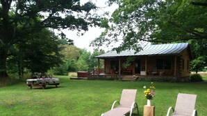 A rustic cabin with a porch, a picnic table, and two lounge chairs in a grassy area. - Simple.  Rustic.  Luxury. (Monterey)
