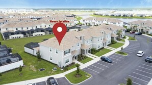 A residential area with multiple two-story houses, a parking lot, and a clear sky. - Astonishing Home Private Pool 4830 (Kissimmee)