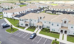 Una zona residencial con varias casas de dos pisos, un estacionamiento y un cielo despejado.