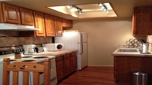 A compact kitchen with wooden cabinets, a stove, a microwave, a refrigerator, and a small sink. - Resort Condo/Relax/ enjoy the outdoors/mountains. Easy access in Winter/ Ruidoso (Ruidoso)