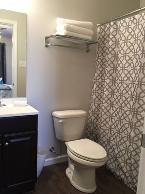A bathroom with a toilet, a sink, a towel rack, and a shower curtain.