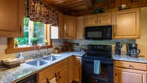A kitchen with wooden cabinets, granite countertops, a black stove, and a microwave.