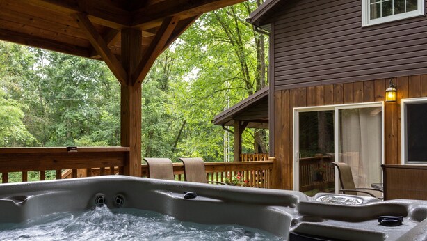 A hot tub on a wooden deck with a view of a forested area.