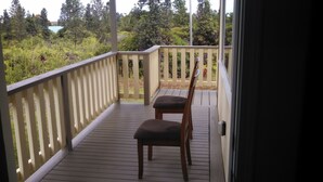 A wooden deck with a railing, a chair, and a view of a natural landscape.