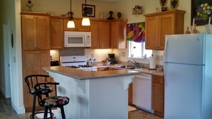 A kitchen with wooden cabinets, a white stove, a microwave, a refrigerator, and a small island with a sink.