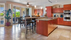 A modern kitchen with a central island, wooden cabinets, and stainless steel appliances. - The Maui Escape - Spectacular 2.5 Bdr Penthouse -Oceanfront Resort-Owner Direct! (Wailea)