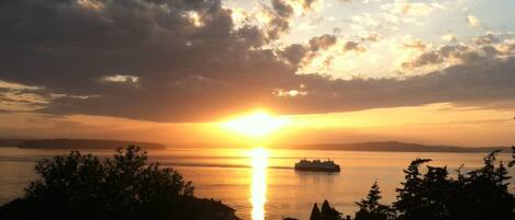 A sunset over a body of water with a ship in the distance.