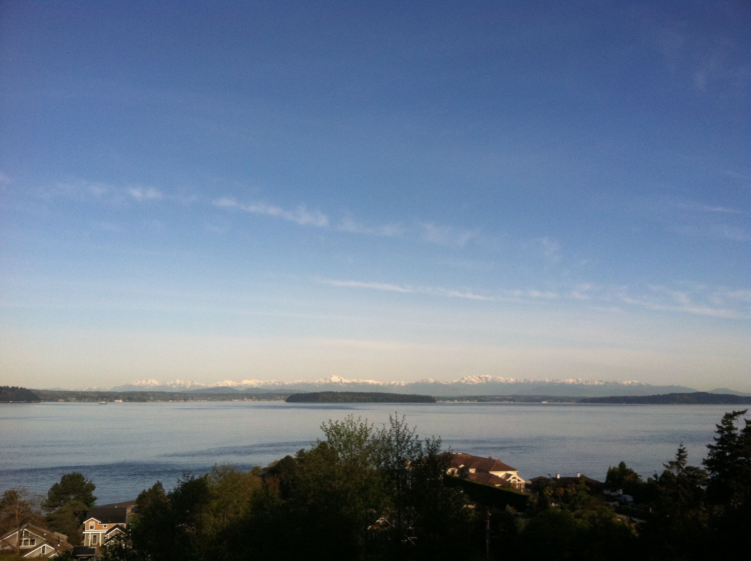 A lake with a mountain range in the background and houses in the foreground.