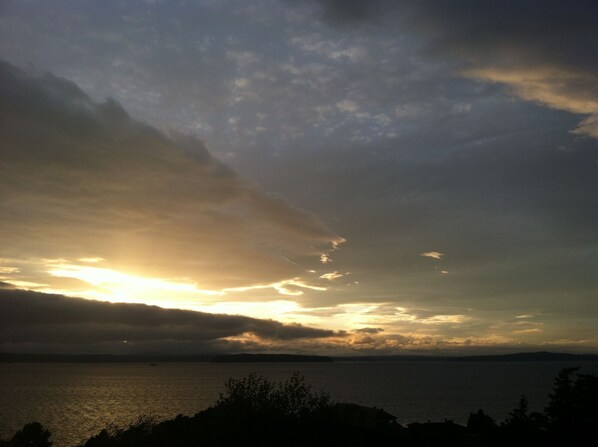 A coastal sunset with clouds over the water. - No cleaning fee. Close to downtown via direct bus. Private & beautiful view. (Seattle)