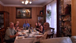 A dining room with wooden paneling, a chandelier, and a table set for a meal. - Ambassador B & B Guest Home (Stratford)