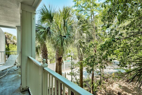 A balcony with a view of a landscaped area including palm trees and a pathway.