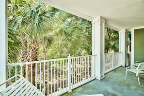 A covered porch with white railings, a bench, and a table.