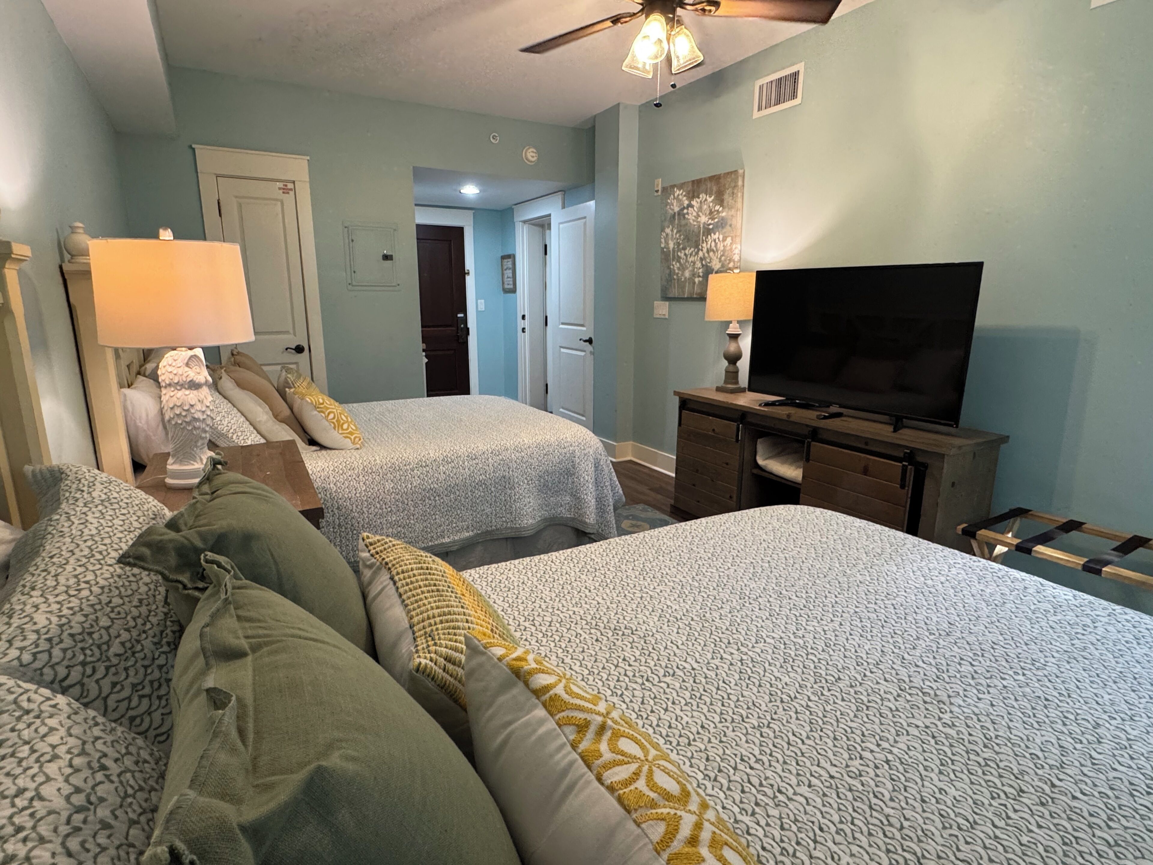 Ein Schlafzimmer mit zwei Betten, einem Fernseher und einem Deckenventilator.