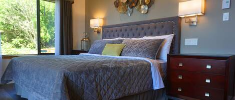 A bedroom with a large bed, a dresser, wall sconces, and a decorative wall piece.