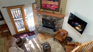 A living room with a stone fireplace, leather armchairs, a sofa, and a TV mounted on the wall. - Townhouse, Downtown Jackson Hole By The Ski Slopes, 5 Miles To Grand Teton Park (Jackson)