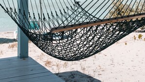 A hammock under a wooden structure on a beach with clear skies. -  Starfish Beach Cottage (exuma)