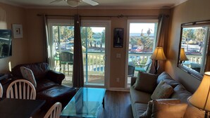 A living room with a glass table, leather sofa, and a view of the outdoors through large windows. - Oceanfront, One-Bedroom & Balcony, 50" Flat TV, Aug. 30- Sept.3- SPL Rates! (Isle of Palms)