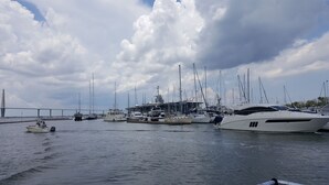 A marina with various boats docked, a large bridge in the background, and a cloudy sky. - Oceanfront, One-Bedroom & Balcony, 50" Flat TV, Aug. 30- Sept.3- SPL Rates! (Isle of Palms)