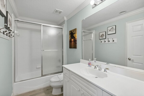 A bathroom with a glass-enclosed shower, a white sink, and a large mirror. - Stunning Ocean Views | Ocean Park Penthouse | Garage Access | Close to Beach (Fernandina Beach)