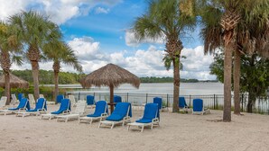 A beach with rows of sun loungers and thatched umbrellas, palm trees, and a view of the water. - Bahama Bay Highest Rated, best Location 3BR/2Bath, Recently Renovated 3rd Floor (Davenport)