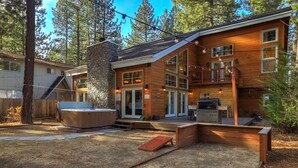 Une maison moderne en bois, dotée d’une cheminée en pierre, d’un jacuzzi et d’une terrasse.