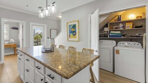 A kitchen with a granite countertop, a built-in oven, and a laundry area with a washing machine and dryer. - Beautiful Town Home Beach Rental In Perdido Key Florida - Pool + Beach Access (Perdido Key)