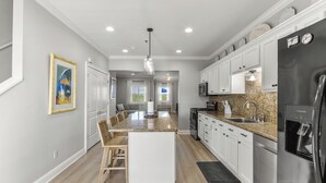 A modern kitchen with white cabinetry, granite countertops, and stainless steel appliances. - Beautiful Town Home Beach Rental In Perdido Key Florida - Pool + Beach Access (Perdido Key)