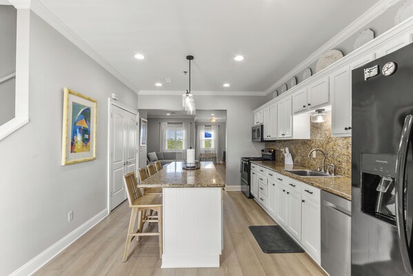 A modern kitchen with white cabinetry, granite countertops, and stainless steel appliances. - Beautiful Town Home Beach Rental In Perdido Key Florida - Pool + Beach Access (Perdido Key)