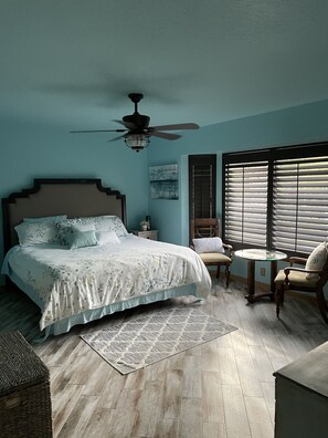 Relax in this serene bedroom with a large bed, ceiling fan, and comfortable seating area.