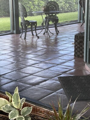 Enjoy outdoor dining or relaxation in this serene patio area with a glass door offering a view of the surrounding greenery.