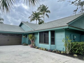 Stunning home with a garage, front porch, and garden, set amidst lush palm trees.