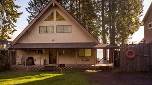 A two-story wooden cabin with a porch, a covered deck, and a fenced yard. - Waterfront Getaway, Beautiful Hood Canal (Brinnon Wa)