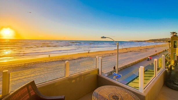 Un balcón con vistas a la playa durante el atardecer, una farola y un cartel que dice "San Rafael".