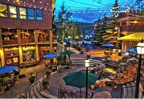 An outdoor courtyard with tables and chairs, string lights, and potted plants. - Ground floor, remodeled, 3 bedroom condo is 10 minutes to Winter Park Ski Resort (Winter Park)