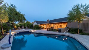 A swimming pool with a tiled deck, surrounded by lounge chairs and a patio area with outdoor lighting. - Hidden, Lush Treasure Close to Everything...Your Own Private Resort! (Mesa)
