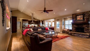 A spacious living room with a leather sofa, a glass coffee table, and a stone fireplace. - Hidden, Lush Treasure Close to Everything...Your Own Private Resort! (Mesa)