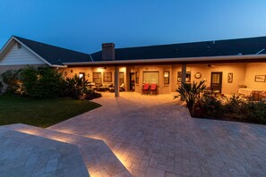 A two-story house with a covered patio area, a brick driveway, and a well-maintained lawn. - Hidden, Lush Treasure Close to Everything...Your Own Private Resort! (Mesa)