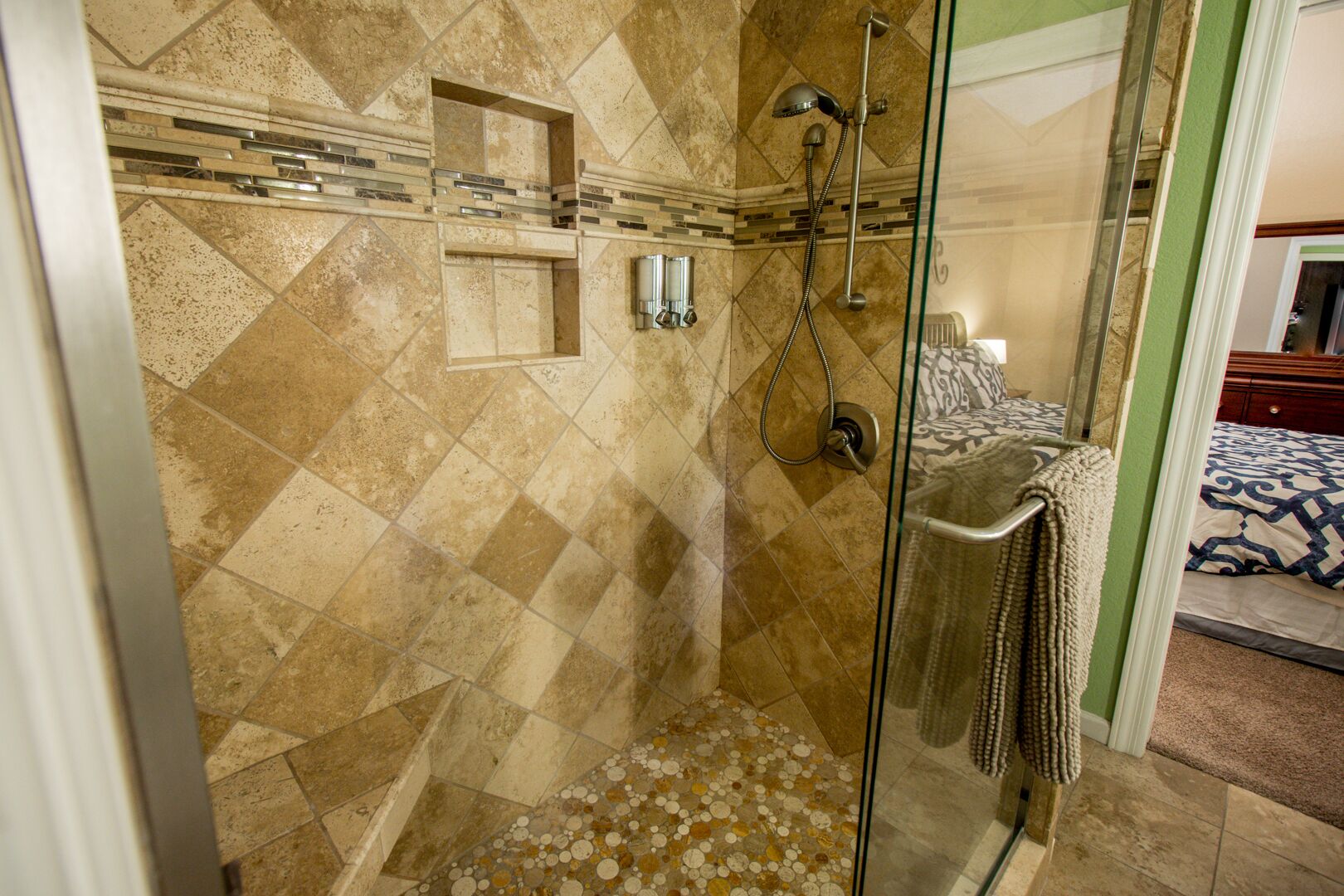A shower with a glass door, a towel rack, and a showerhead.