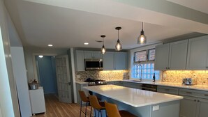 Une cuisine moderne dotée d’un grand îlot central, de tabourets de bar et de luminaires suspendus.
