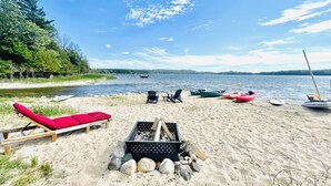 Une plage avec des chaises longues, des kayaks et une planche de paddle.