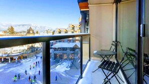 A balcony with a view of a snowy town square, a table, and chairs. - Top Floor. Top Views. Top of Whistler. 
The Penthouse at the Carleton Lodge. (Whistler)