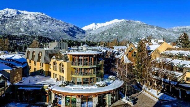 A hotel with a central courtyard, multiple floors, and a mountain backdrop. - Top Floor. Top Views. Top of Whistler. 
The Penthouse at the Carleton Lodge. (Whistler)