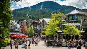 A bustling square with traditional buildings, a prominent hotel named "The Crystal," and a mountain backdrop.