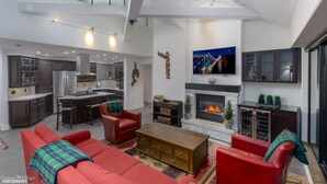 A spacious living area with a fireplace, red sofas, a kitchen, and a dining area. - Top Floor. Top Views. Top of Whistler. 
The Penthouse at the Carleton Lodge. (Whistler)