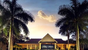 A hotel entrance with a sign reading "Falling Waters," surrounded by palm trees and a landscaped garden. - Relax on the oversized lanai featuring an outdoor kitchen and mid-water view. (Naples)
