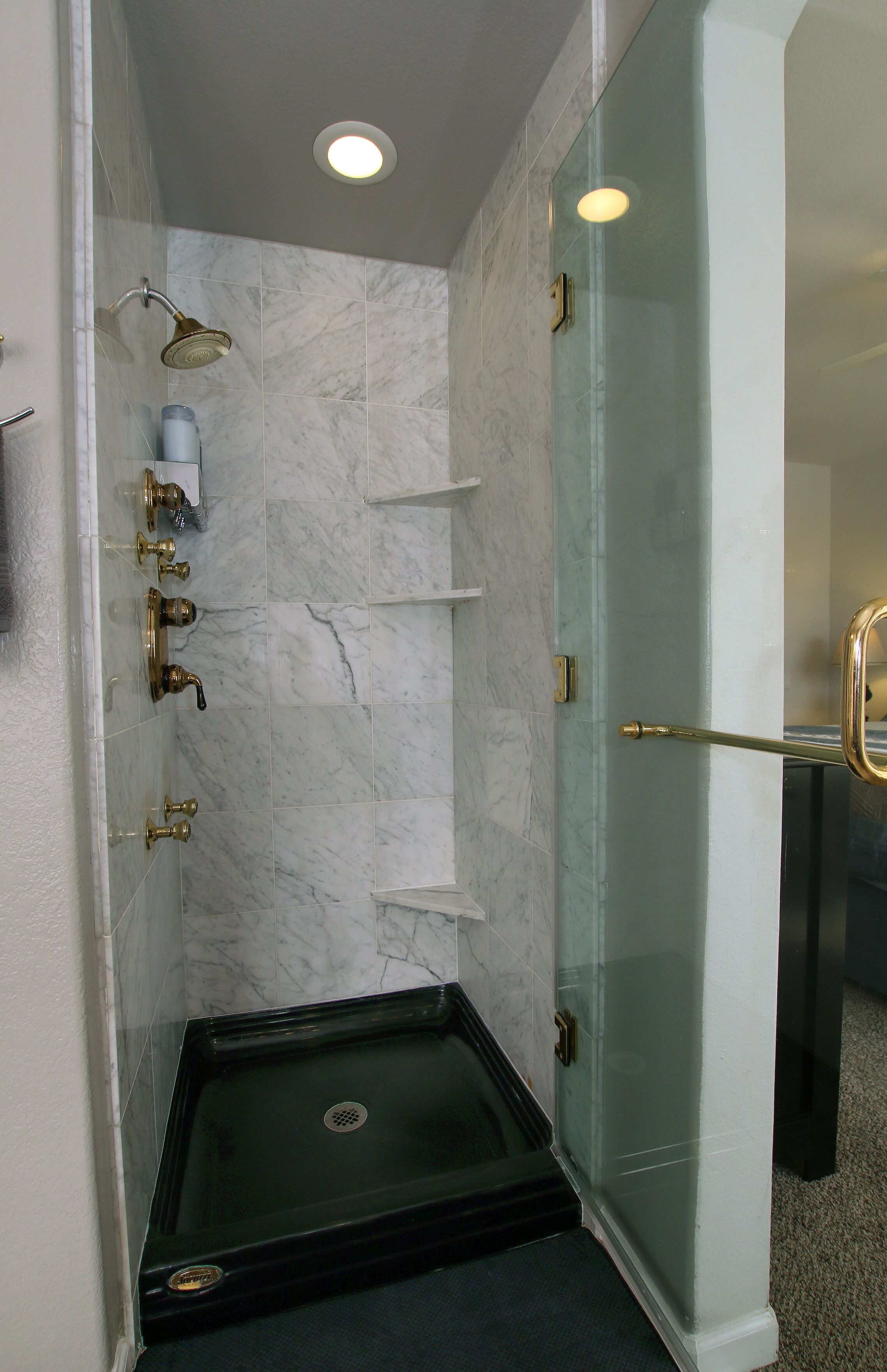 Eine Dusche mit Glastür, Duschbrause und integrierter Sitzgelegenheit.