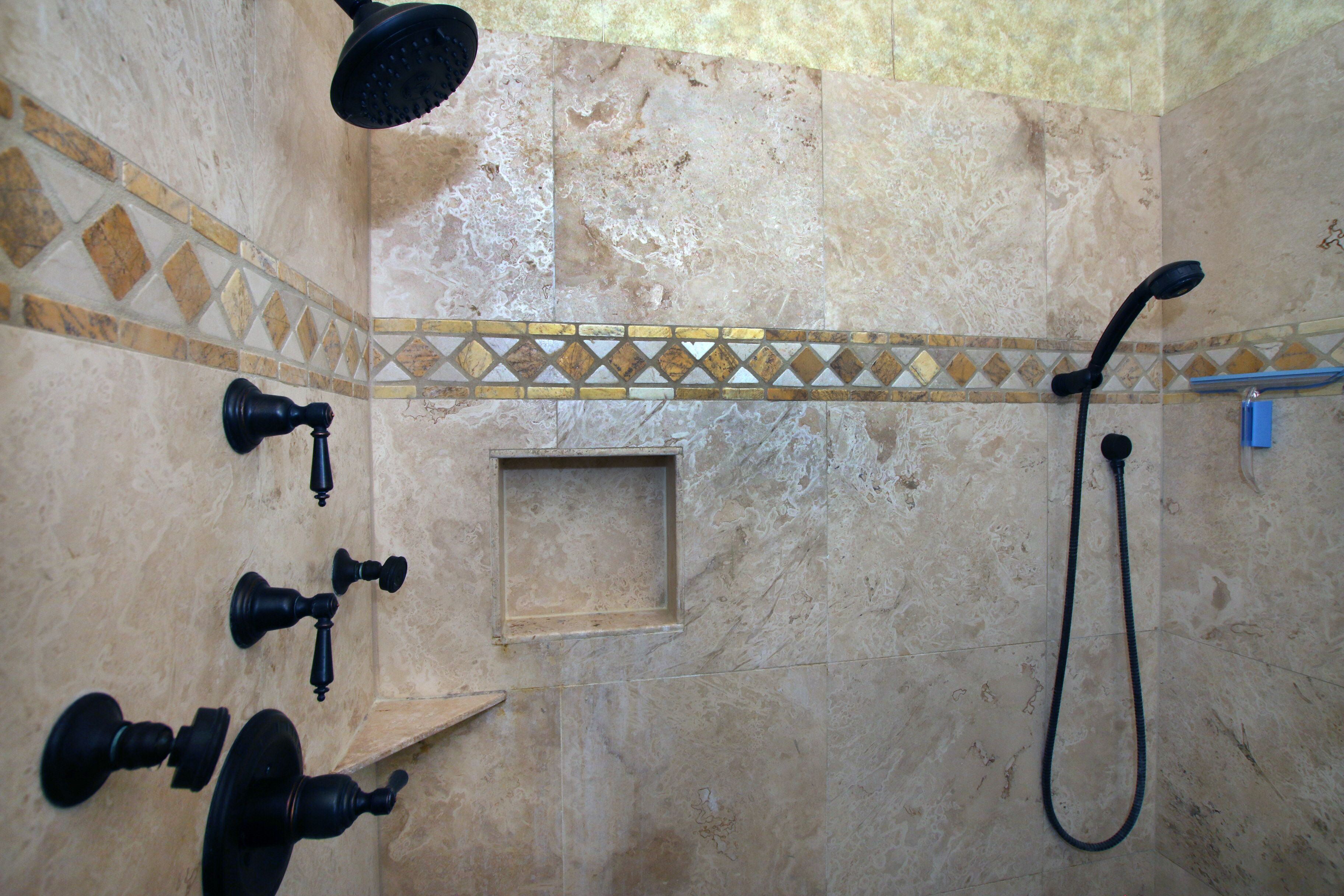 A bathroom with a shower, a handheld showerhead, a handheld faucet, and a small wooden shelf.